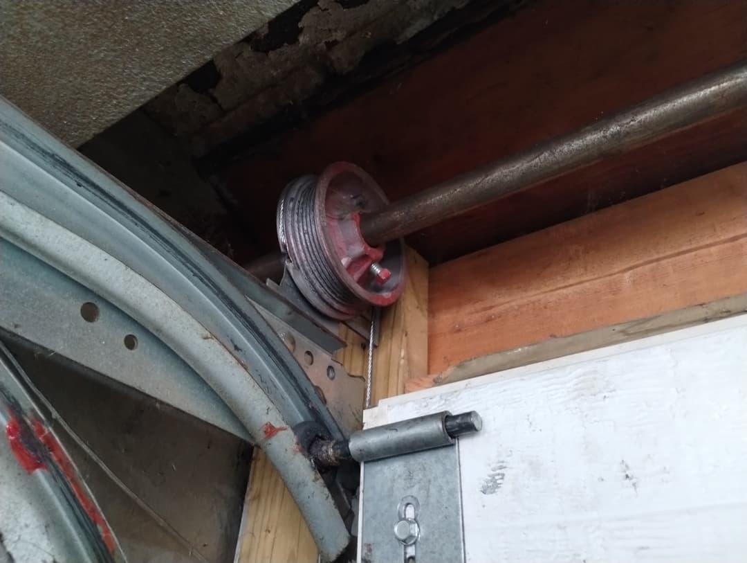 Garage door cable and drum assembly near the top corner of the door track.