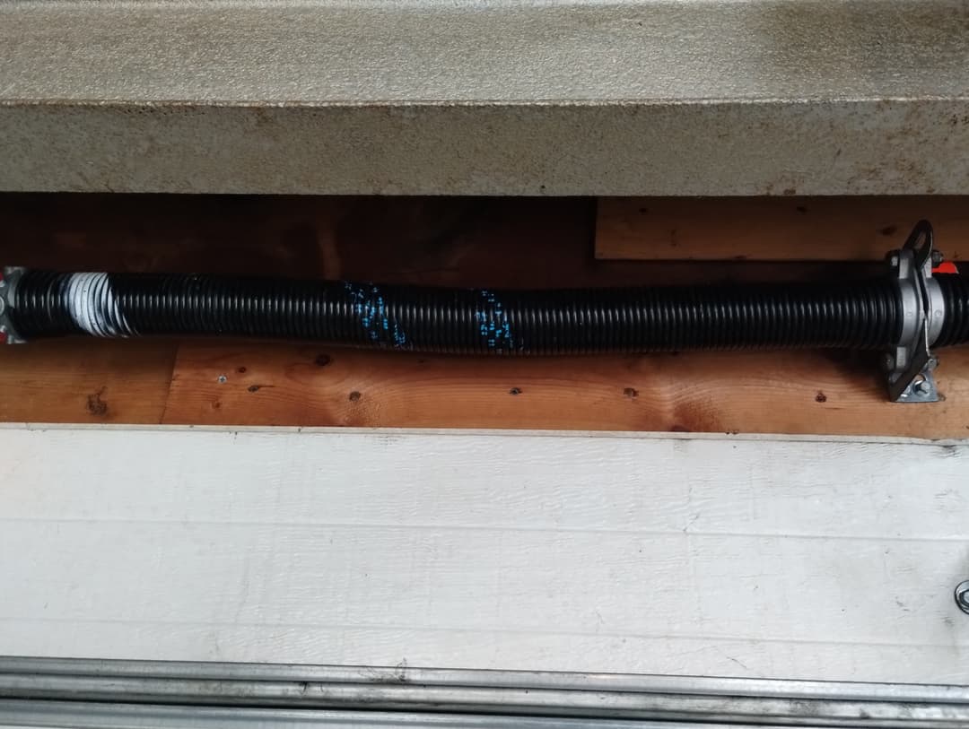 Garage door torsion spring mounted above the door.
